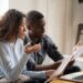 couple looking at a piece of paper and their computer having a serious discussion