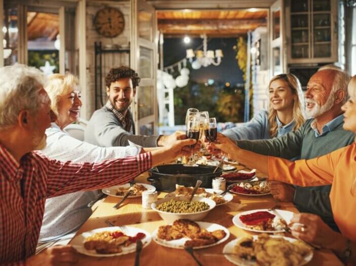 family around the thanksgiving table putting their glasses together cheersing