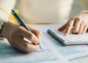 person filling out and writing information on official documents