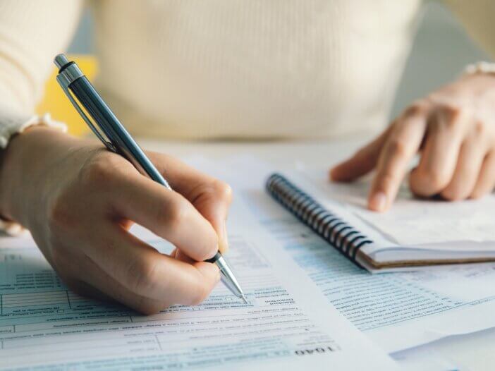 person filling out and writing information on official documents