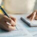 person filling out and writing information on official documents