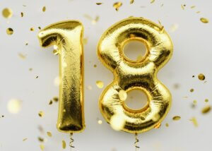 there are gold balloons that say 18 to signify that the person is becoming an adult.