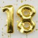 there are gold balloons that say 18 to signify that the person is becoming an adult.