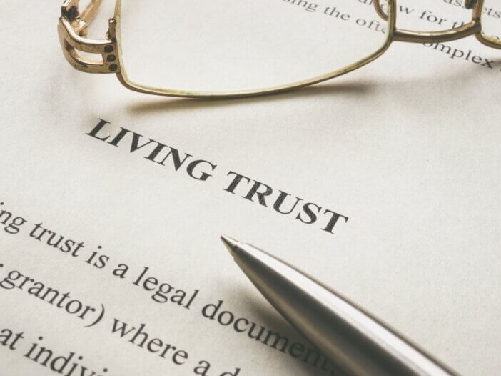 a document that says living trust and there are reading glasses on the top of it