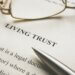 a document that says living trust and there are reading glasses on the top of it