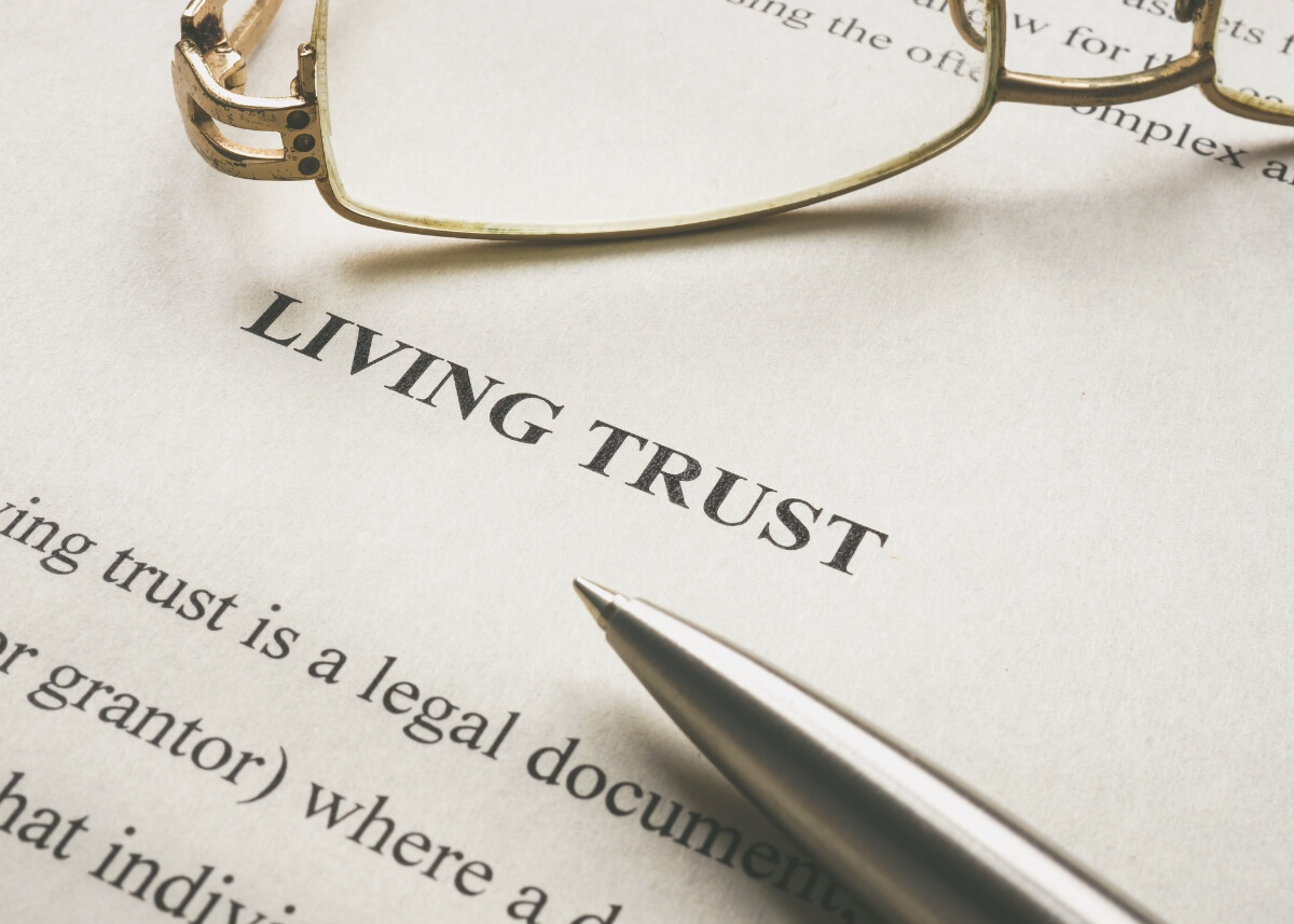 a document that says living trust and there are reading glasses on the top of it