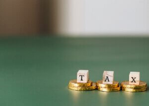 a picture of a stack of three golden coins and on top of each coin has a letter- that spells out tax