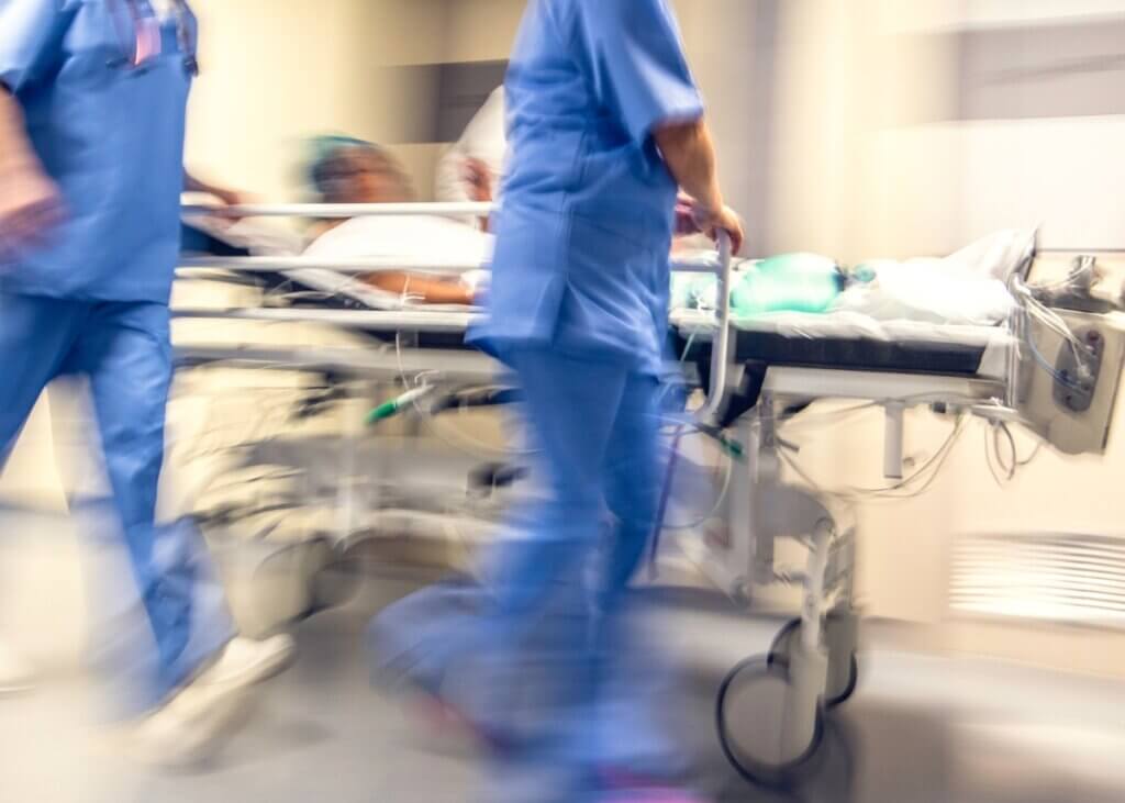 a picture of an emergency room bed being rushed by nurses with a patient lying in the bed. it is blurred and gives a chaotic and rushed feel