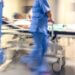 a picture of an emergency room bed being rushed by nurses with a patient lying in the bed. it is blurred and gives a chaotic and rushed feel