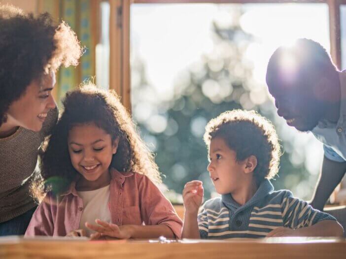 An image of a family of four with a mother, father, and two kids talking and spending time together.