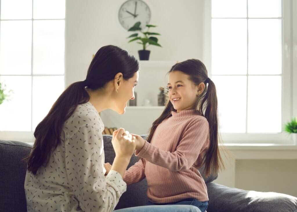 a mom and her younger daughter talking and the mom is holding the daughters hand talking to her