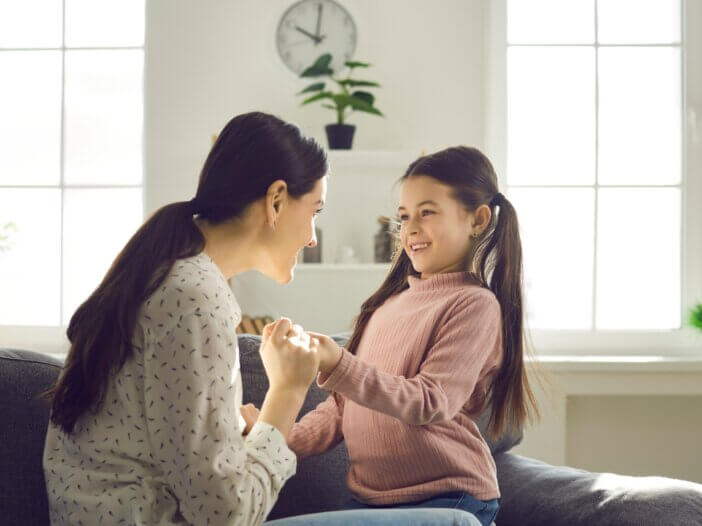 a mom and her younger daughter talking and the mom is holding the daughters hand talking to her