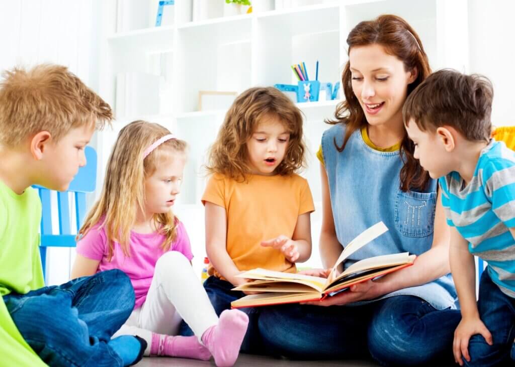 a mom with her four little kids with a book in her lap reading a story to them