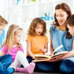 a mom with her four little kids with a book in her lap reading a story to them