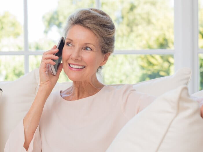 a woman on the phone talking with someone with a big smile making a connection.