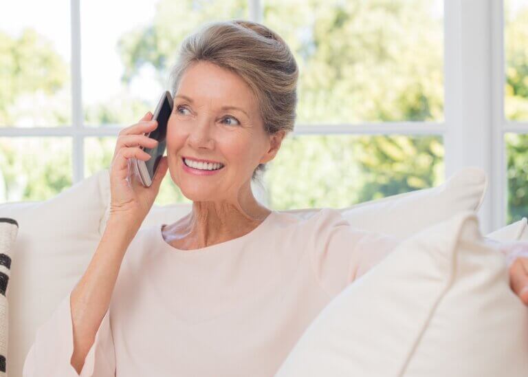 a woman on the phone talking with someone with a big smile making a connection.