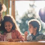 a younger couple with their two younger kids. they are sitting at the kitchen table all laughing together